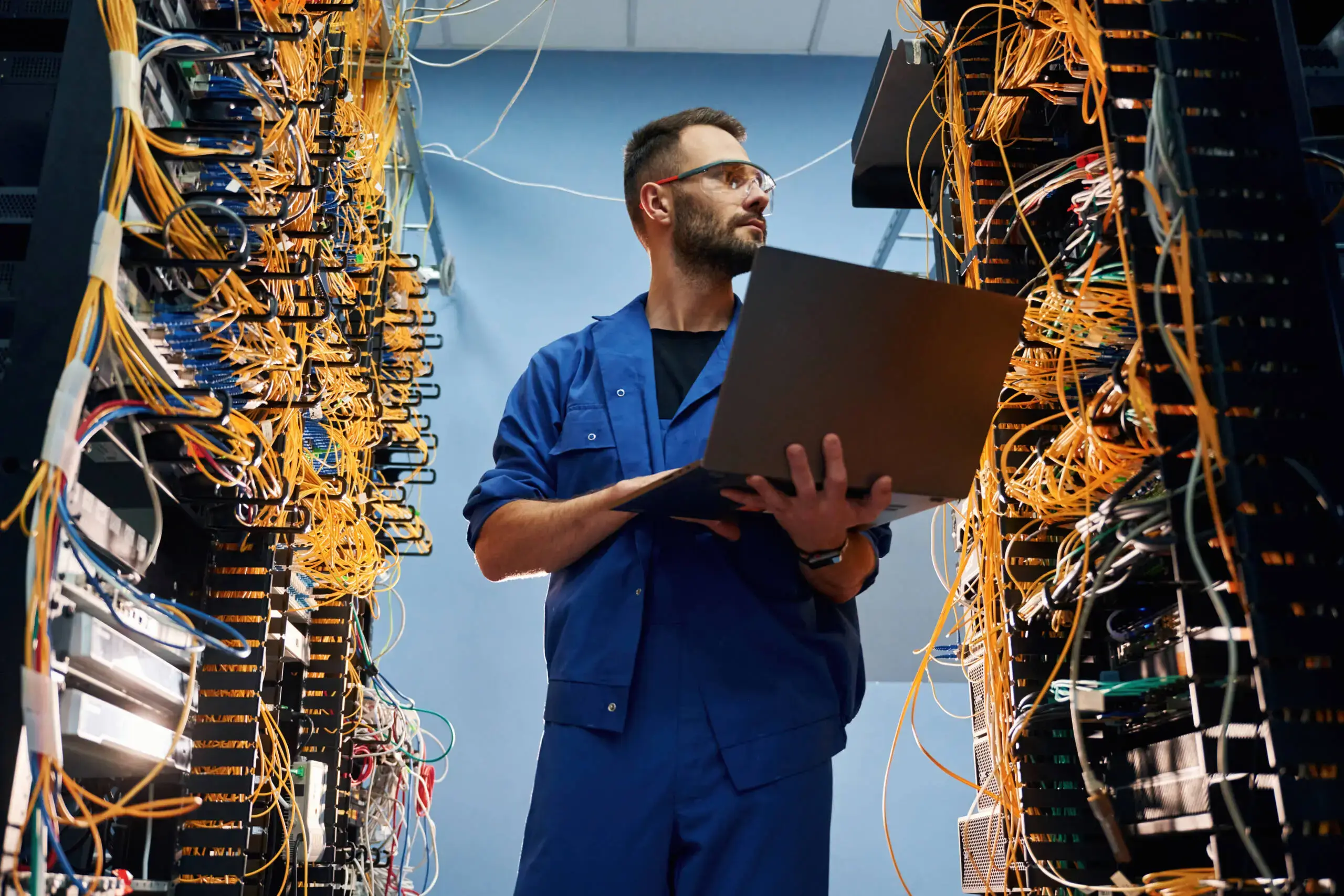 Engineer with a laptop inspecting cables